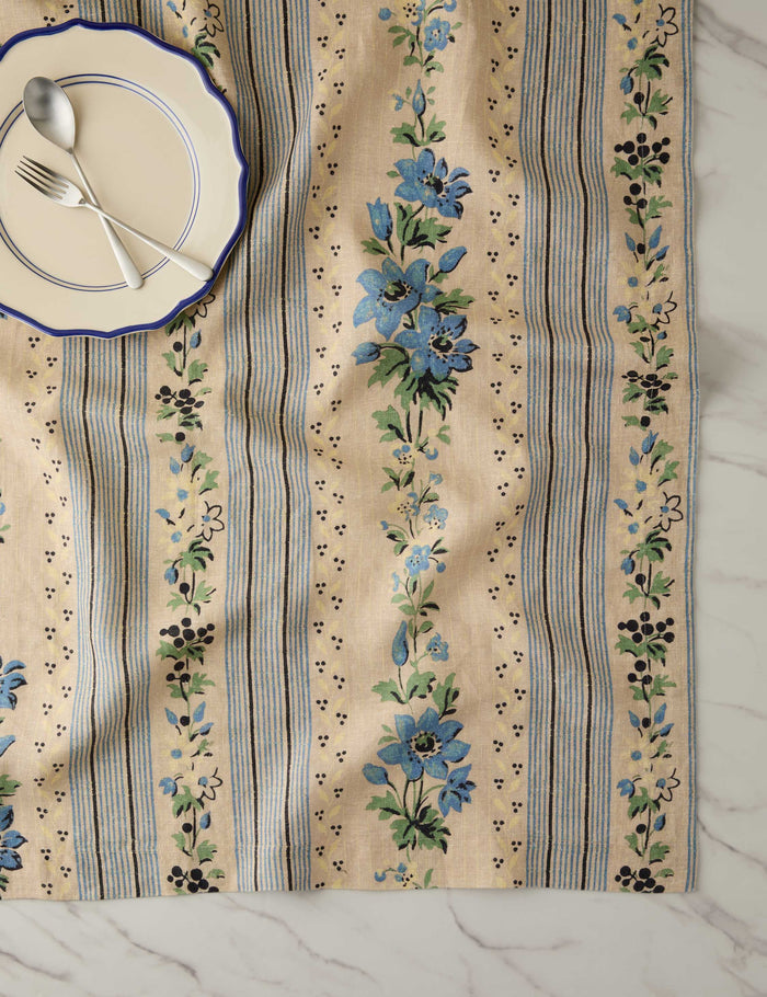 #color::azure #size::large #size::small | Overhead view of a place setting with the Golden floral stripe linen tablecloth by Heidi Caillier underneath