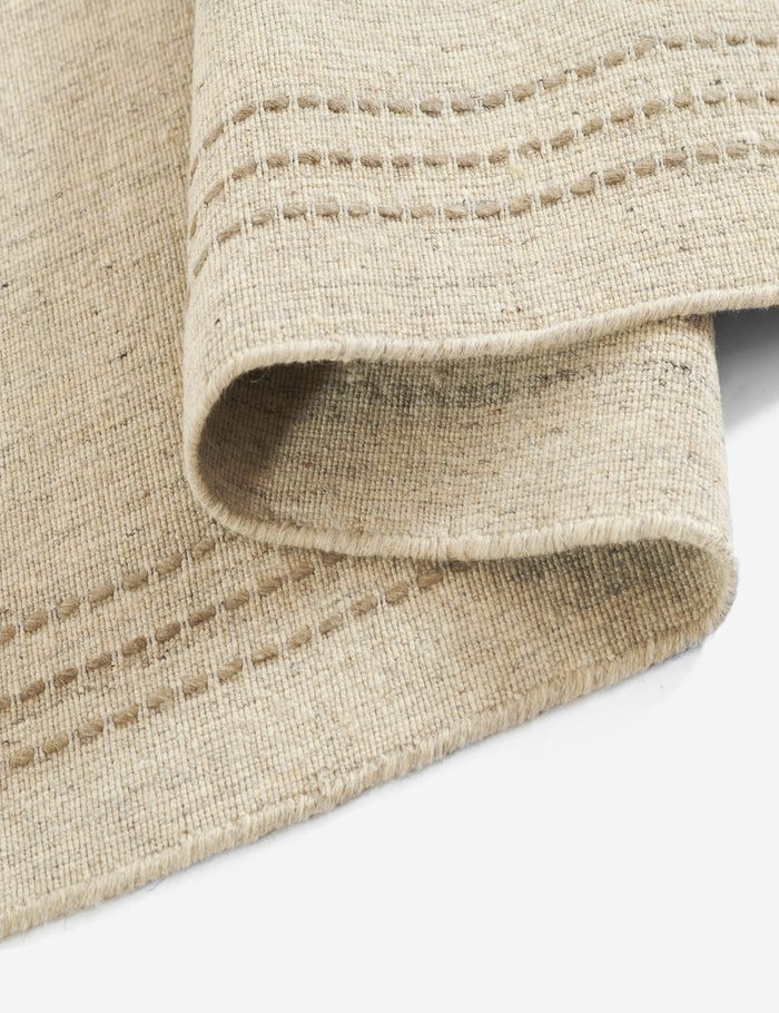 #size::2-3--x-8--runner #size::3-6--x-5-6- #size::5--x-8- #size::8--x-10- #size::9--x-12- | Close up of the edge of the Greco low pile wool rug with accent border stitching.